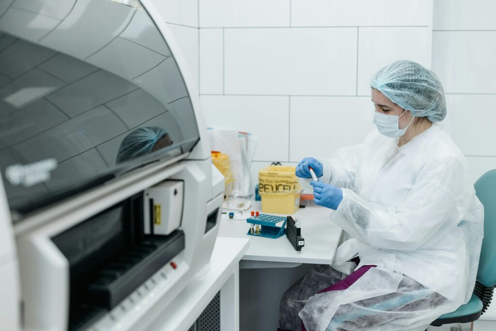 Scientist in protective gear examining samples in a medical lab setting, focusing on research.